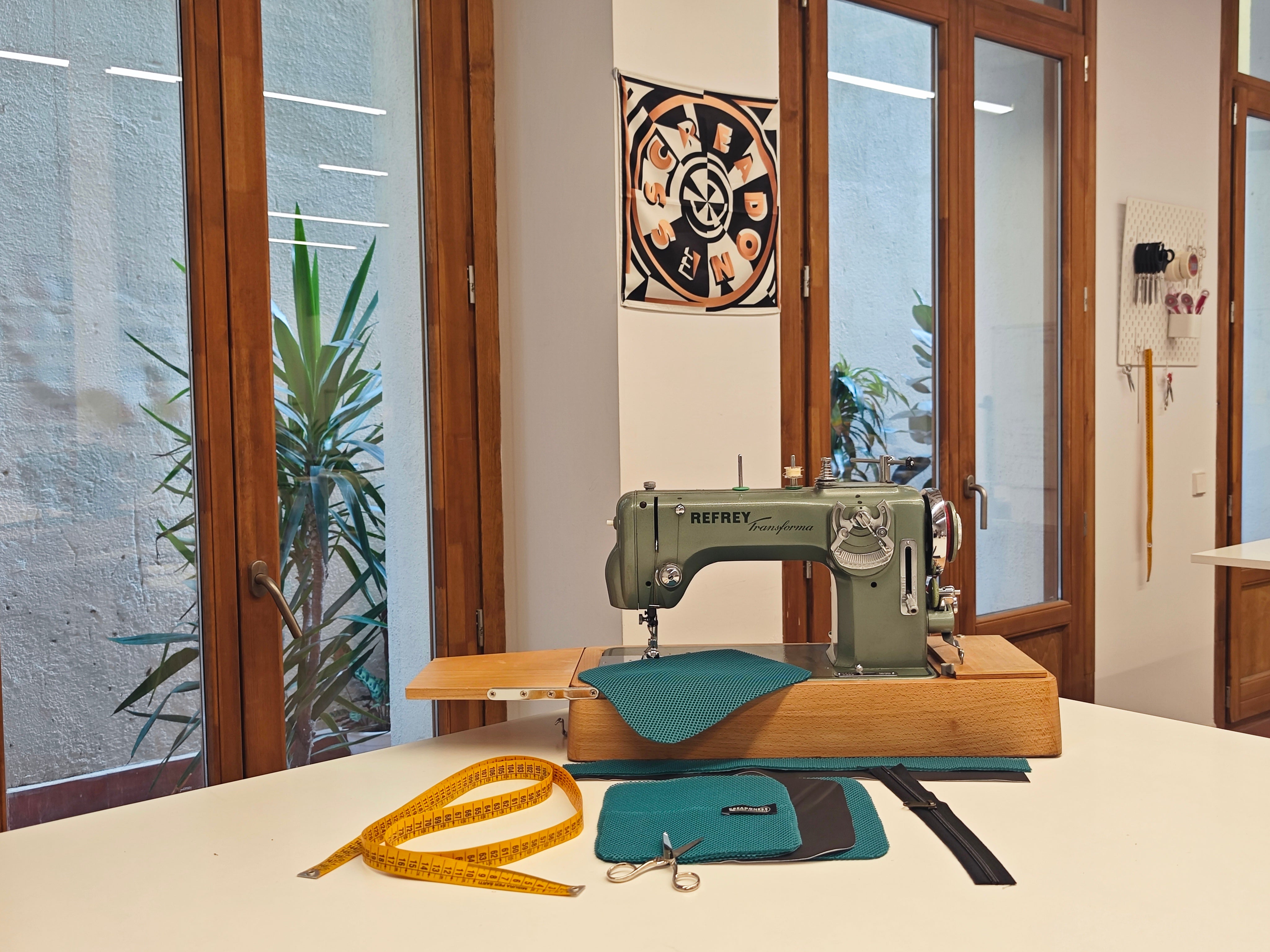 Máquina de coser junto a materiales y herramientas de costura.