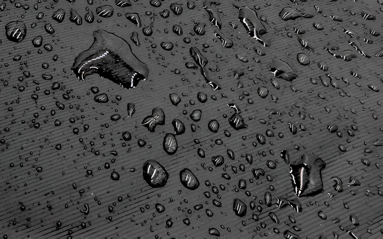 Tejido resistente al agua mostrado en detalle, con gotas de agua rociadas por encima demostrando su resistencia al agua.