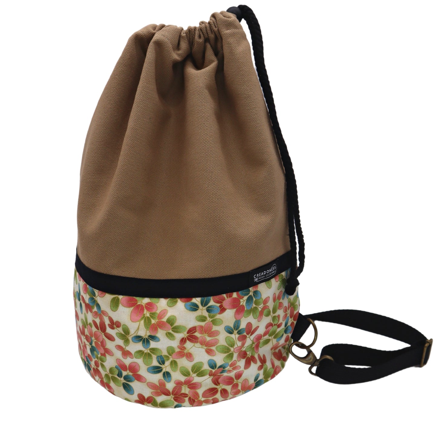 Mochila Petate de base circular de 24 cm de diámetro hecha de algodón. Su medida es de 38 cm de alto y 37 cm de ancho. Posee un asa bandolera para cruzar. En el interior tiene un bolsillo de 26 cm y un bolsillo oculto de 15 cm de profundidad.
