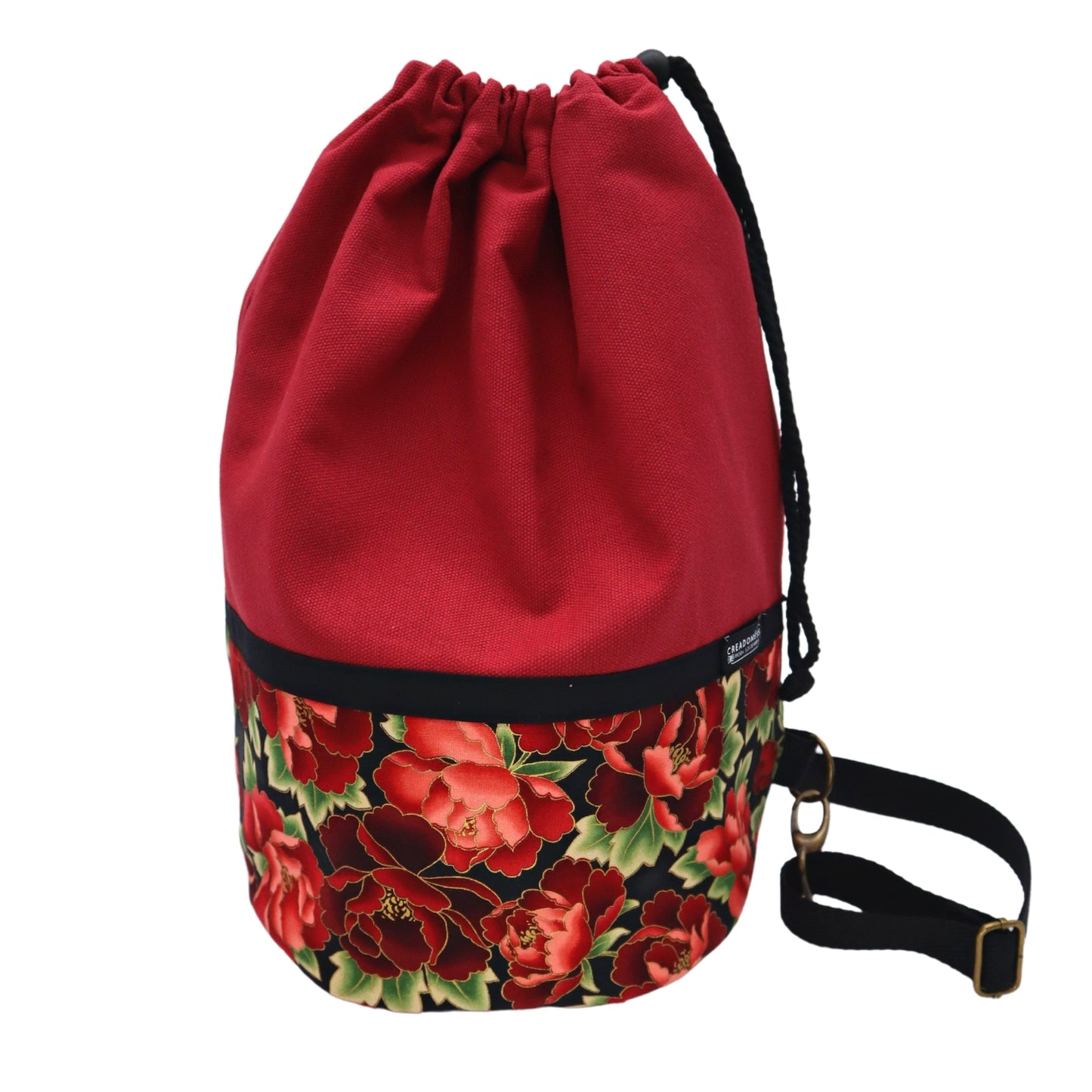 Mochila Petate de base circular de 24 cm de diámetro hecha de algodón. Su medida es de 38 cm de alto y 37 cm de ancho. Posee un asa bandolera para cruzar. En el interior tiene un bolsillo de 26 cm y un bolsillo oculto de 15 cm de profundidad.