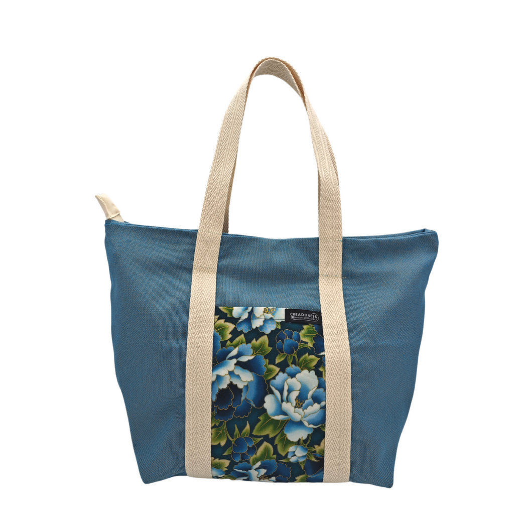 Descubre la Tote Bag Tsubaki Aoi está hecha a mano con suave tela de algodón azul, elaboradas artesanalmente por las mujeres del Programa Social de Creadoness.