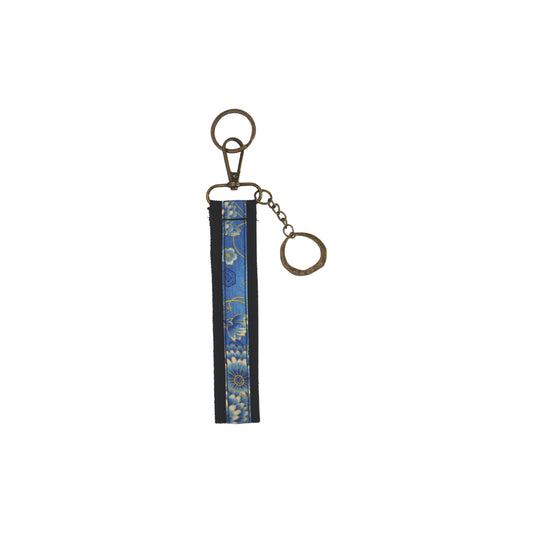 Llavero de algodón de color negro con estampado de flores azules. Su medida es de 14 cm y por su diseño permite colocarlo en la muñeca.