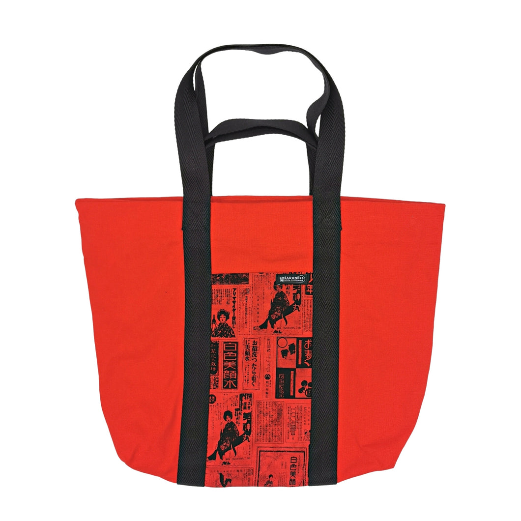 Maxi Bag hecha de algodón de color roja con un bolsillo exterior fondo rojo y con letras y figuras japonesas color negro. Posee cuatro asas de algodón. Su medida es de 46 cm de alto