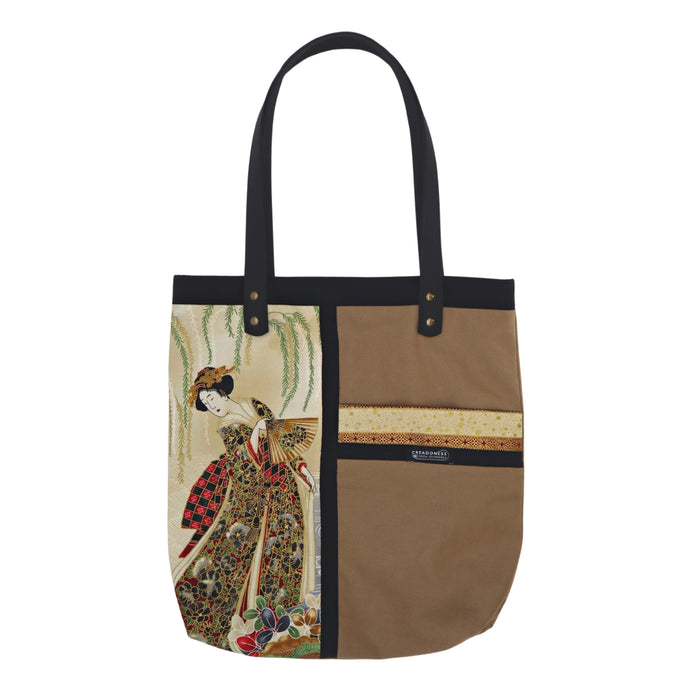 Tote Bag hecha de algodón de color beige. Tiene una estampa que cubre el lado derecho con un diseño japonés que muestra a una geisha bajo una lluvia de pétalos de flores. Posee dos asas de cuerina negra de 70 cm. 