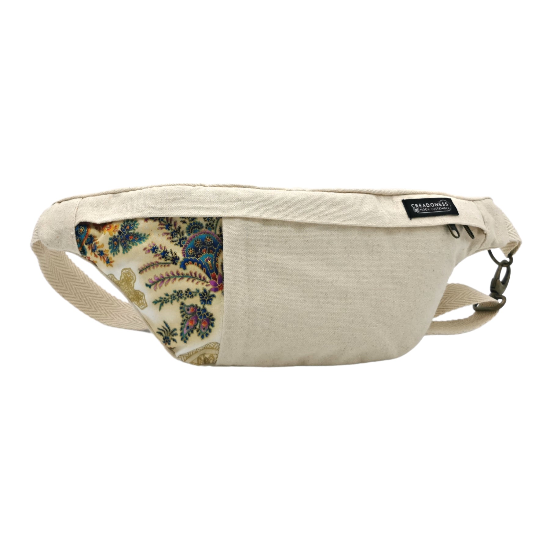 Riñonera hecha de algodón de color blanca con un estampado de flores tipicas de la India. Su medida es de 37 x 18 cm. Con un asa ajustable. 