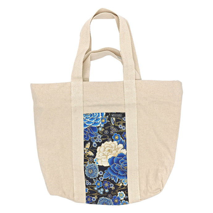 Maxi Bag hecha de algodón de color blanca con un bolsillo exterior con estampado japonés con fondo negro y diseño floral azul y blanco. Su medida es de 46 cm de alto