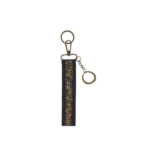 Llavero de algodón de color negro y detalles dorado. Su medida es de 14 cm y por su diseño permite colocarlo en la muñeca.