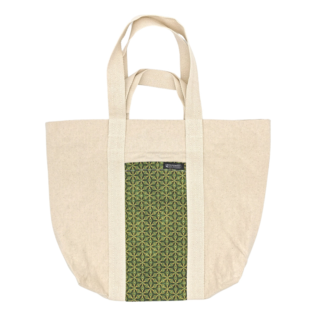 Maxi Bag hecha de algodón de color blanca con un bolsillo exterior con estampado verde y diseño geométrico. Su medida es de 46 cm de alto