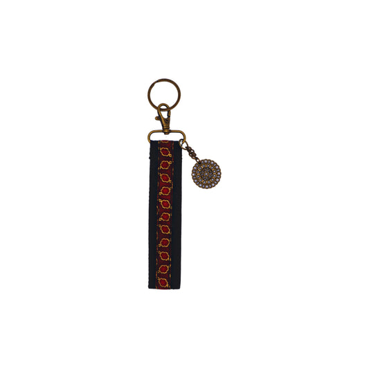Llavero de algodón de color negro con estampado geométrico rojo. Su medida es de 14 cm y por su diseño permite colocarlo en la muñeca.