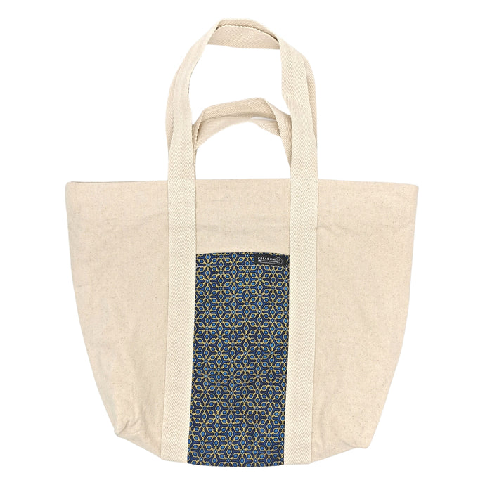 Maxi Bag hecha de algodón de color blanca con un bolsillo exterior con estampado azul y diseño geométrico. Su medida es de 46 cm de alto