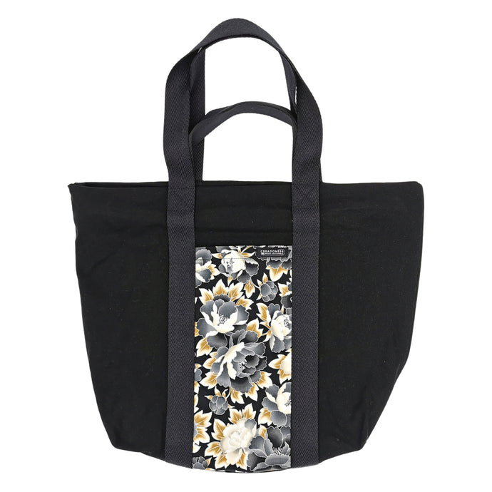 Maxi Bag hecha de algodón de color negra con un bolsillo exterior con estampado de flores japonesas de tres colores: negras, doradas y blancas. Su medida es de 46 cm de alto
