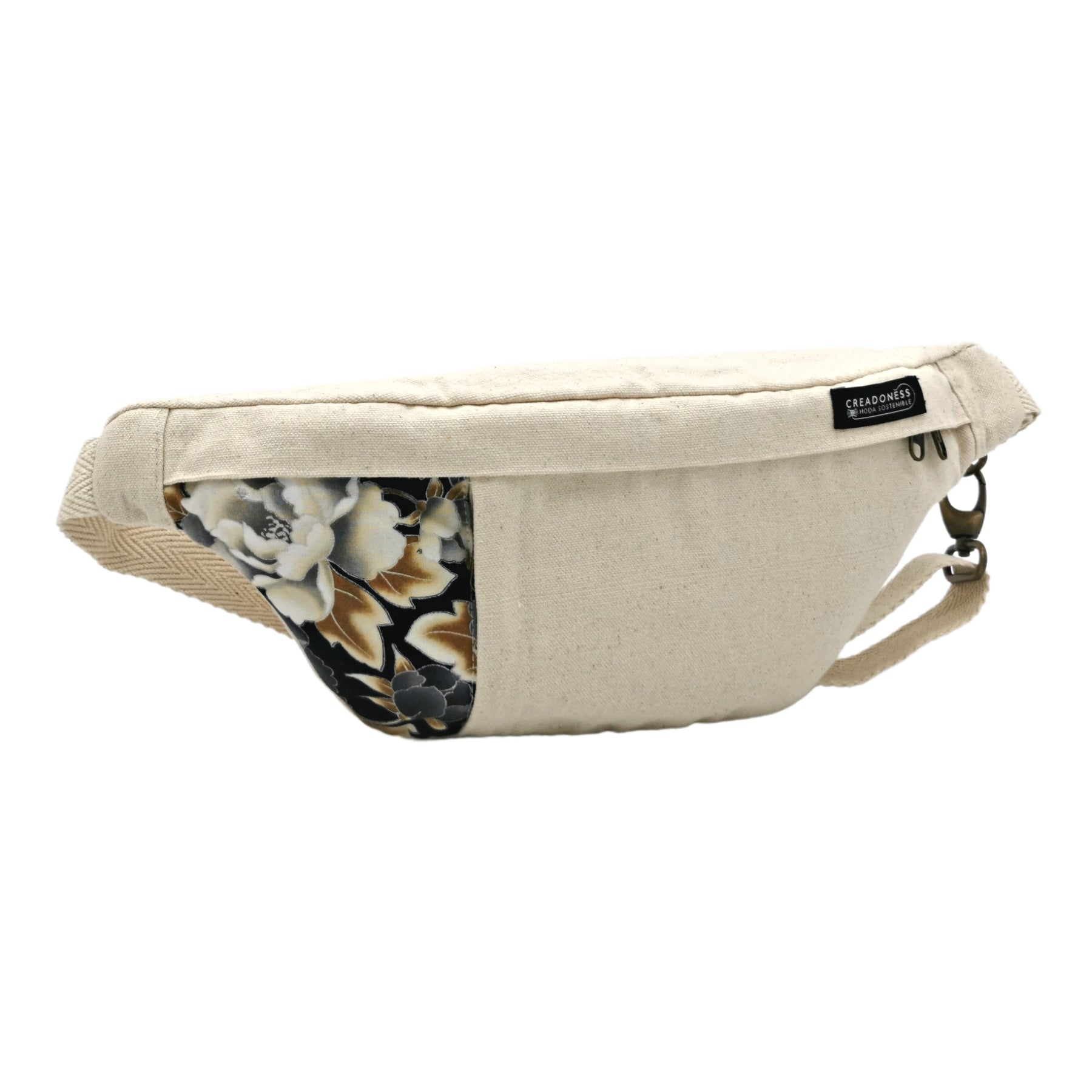 Riñonera hecha de algodón de color blanca con un estampado de flores negras y blancas. Su medida es de 37 x 18 cm. Con un asa ajustable. 