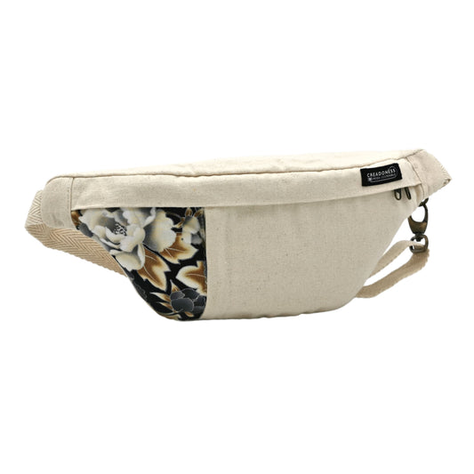 Riñonera hecha de algodón de color blanca con un estampado de flores negras y blancas. Su medida es de 37 x 18 cm. Con un asa ajustable. 